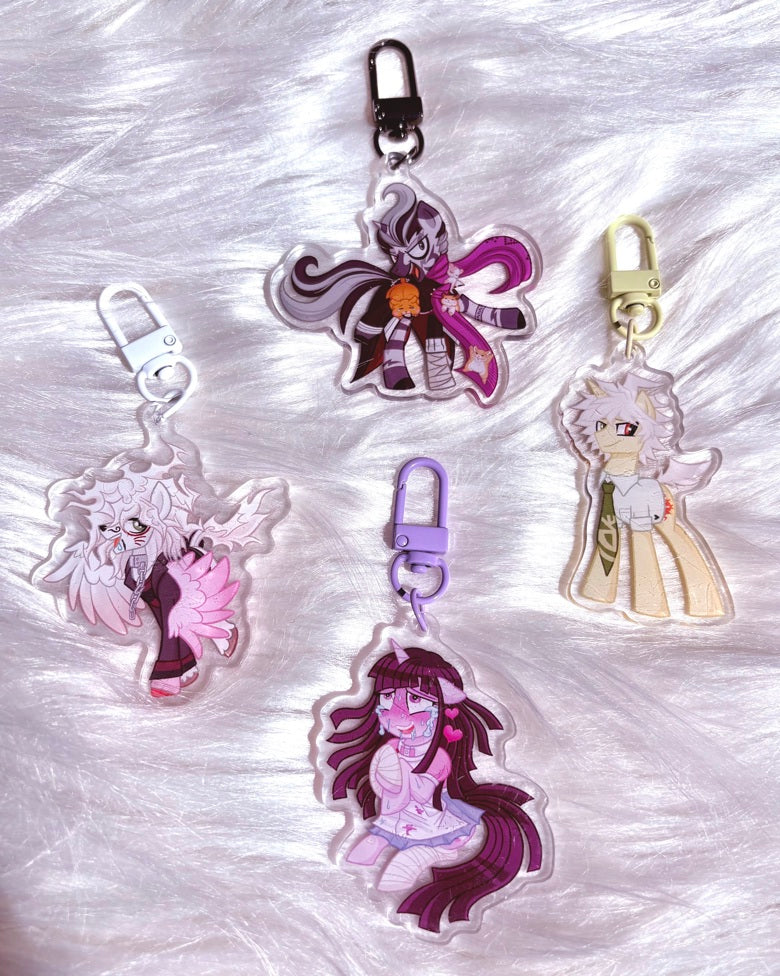 Four anime-style acrylic keychains with different character designs, displayed on a white faux fur background.